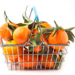A wire basket filled with tangerines against a white background.