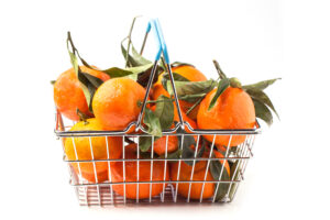 A wire basket filled with tangerines against a white background.