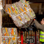 A worker takes down a bale of recycled materials.