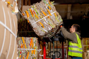 A worker takes down a bale of recycled materials.