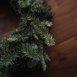 A close up view of a Christmas wreath against hardwood floors.