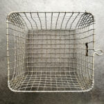 A basket made of steel wire forms sitting on the concrete floor.