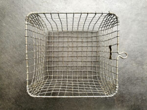 A basket made of steel wire forms sitting on the concrete floor.