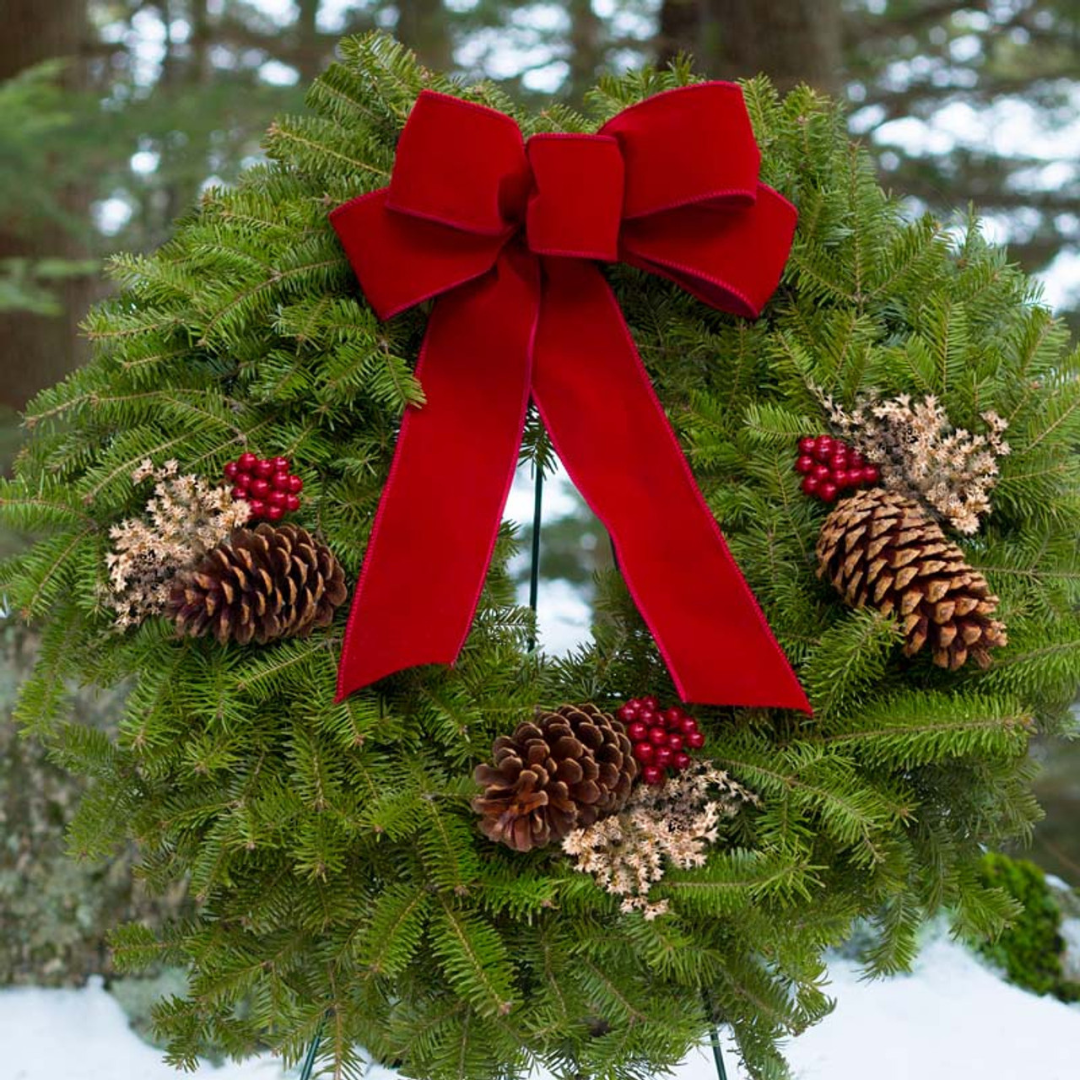 Christmas wreath in the snow with a red ribbon, made using Oregon Wire's wreath forms.